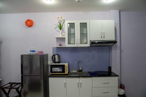 a kitchen with white cabinets and a refrigerator at HT Hotel Apartment in Ho Chi Minh City