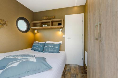 a bedroom with a bed with blue pillows on it at Luxe Houseboat Skoft in Grou