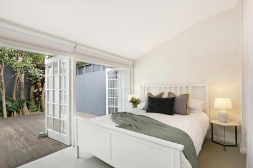 a white bedroom with a bed and a patio at Paddington Garden Cottage with fast Wifi in Sydney
