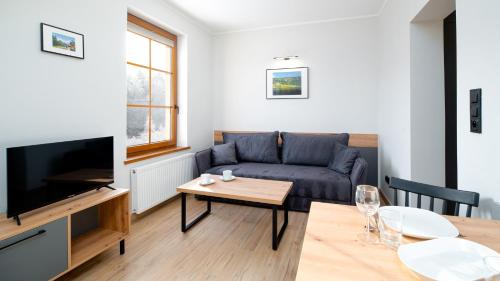 a living room with a couch and a table at Wonder Home - Apartamenty Karkonosz blisko wyciągów narciarskich, szlaków i restauracji in Karpacz