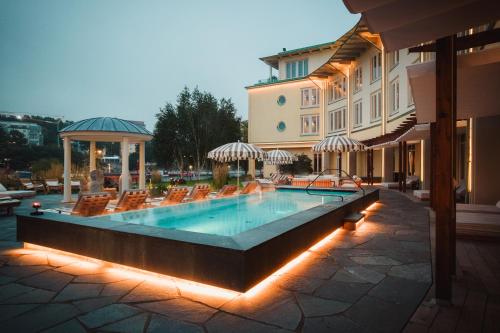 einen Pool mit Stühlen und ein Gebäude in der Unterkunft Ad Astra by Elite - Hotel, Spa & Resort in Södertälje