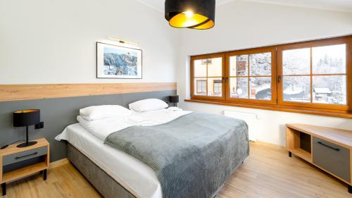 a bedroom with a bed and a desk and windows at Wonder Home - Apartamenty Karkonosz blisko wyciągów narciarskich, szlaków i restauracji in Karpacz