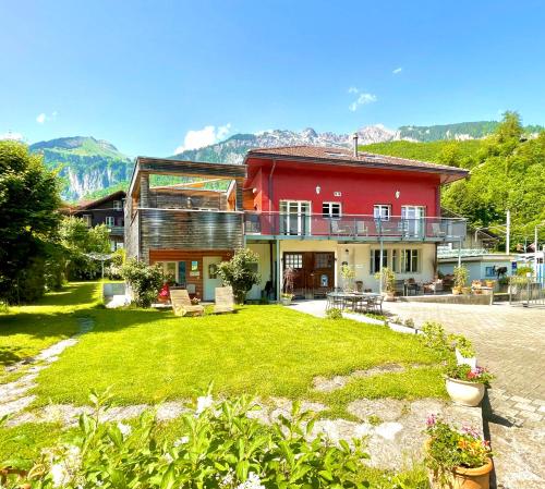 a red house with a yard in front of it at Romantic Lake & Mountain apartment Pure Swissness in Brienz