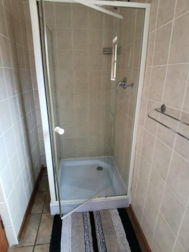 a shower with a glass door in a bathroom at Robs Place in Potchefstroom