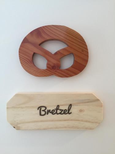 a wooden pretzel sign on a white wall at Chambres d'hôtes A la Fecht Nature et Bien-être in Sondernach