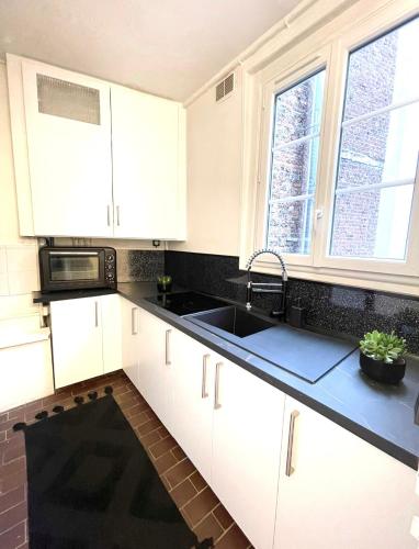 La cuisine est équipée de placards blancs, d'un évier et de fenêtres. dans l'établissement Quai de Seine Tour Eiffel Trocadéro, à Paris