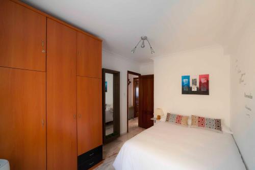 a bedroom with a white bed and wooden cabinets at SJE - Shiny apartment close to the river in Seville