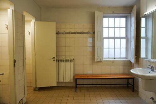 a bathroom with a bench and a sink and a window at HI Guimaraes - Pousada de Juventude in Guimarães