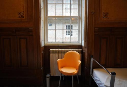 an orange chair sitting in front of a window at HI Guimaraes - Pousada de Juventude in Guimarães