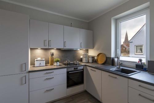 a kitchen with white cabinets and a sink and a window at Ferienwohnung - Vasco da Gama in Petersdorf auf Fehmarn