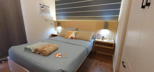 a bedroom with a bed and a nightstand with towels on it at JC SpaceRentals 127B Amani Grand Resort Residences, balcony pool view, Ground floor, 5 mins frm airport, free wifi, Netflix in Pusok