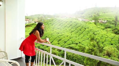 a woman standing on a balcony looking at a tea plantation at Hotel C7 Munnar in Munnar