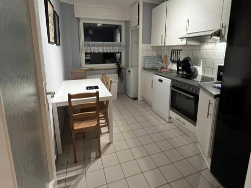 - une cuisine avec des placards blancs, une table et des chaises dans l'établissement Monteurwohnung Neuss, à Neuss