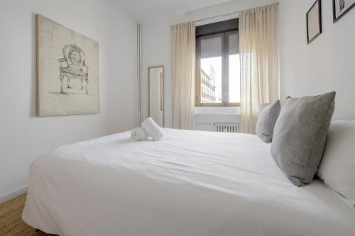 - un lit blanc dans une chambre blanche dotée d'une fenêtre dans l'établissement Luxury Apartamento de 5hab en el centro de Madrid, à Madrid