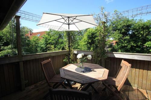 a table and chairs with an umbrella on a deck at Lindenallee 4a - Erholung und Wellness in Westfehmarn