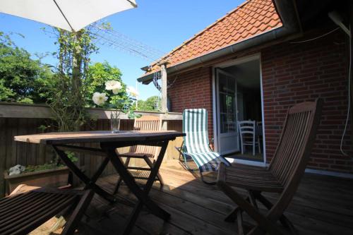 a wooden table and chairs on a deck with an umbrella at Lindenallee 4a - Erholung und Wellness in Westfehmarn