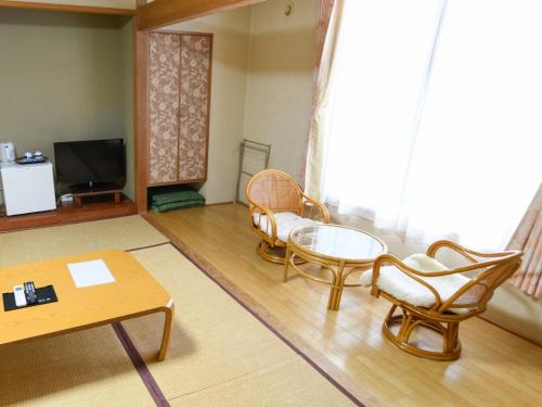a living room with chairs and a table and a tv at Ryokan HANAEMI in Otaru