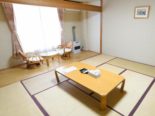 Ryokan HANAEMI في أوتارو: غرفة معيشة مع طاولة قهوة في غرفة