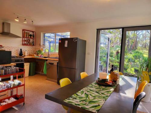 a kitchen with a table and a refrigerator in it at The Yellow Koala - Vibrant Home in Medlow Bath in Medlow Bath