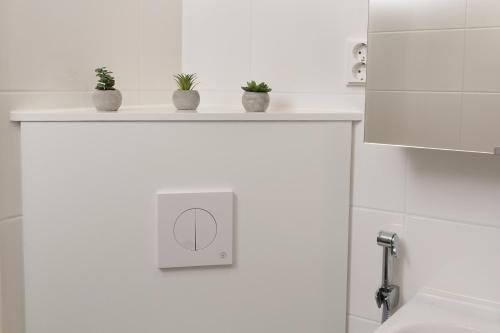 a white bathroom with potted plants on a shelf at Holiday Apartment Aava 3 in Rovaniemi