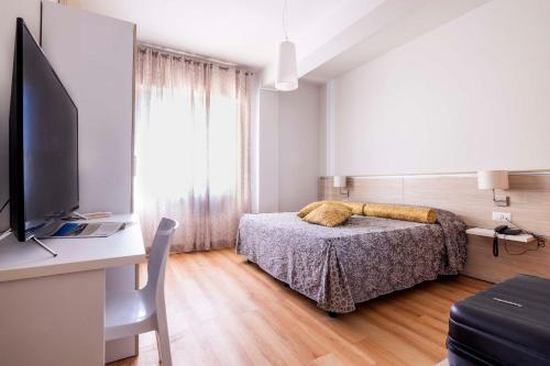 um quarto com uma cama e uma secretária com uma televisão em Hotel Giancarlo em San Benedetto del Tronto