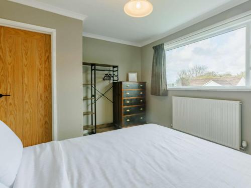 um quarto com uma cama branca e uma janela em 2 Bed in Bude 90312 em Bude