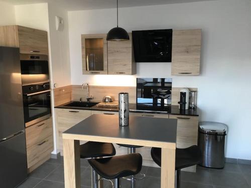 une cuisine avec une table et quelques appareils noirs dans l'établissement Magnifique appartement au Lavandou, au Lavandou