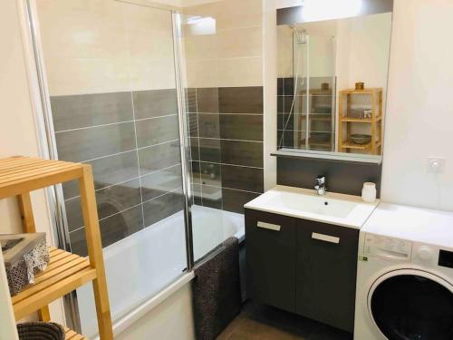 une salle de bain avec douche et lavabo et une machine à laver dans l'établissement Magnifique appartement au Lavandou, au Lavandou