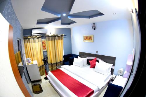 Schlafzimmer mit einem großen Bett und einem Deckenventilator in der Unterkunft Remzy Hotel & Suites, Olomore in Aro