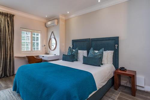 een slaapkamer met een groot bed en een blauwe deken bij Clico Boutique Hotel in Johannesburg