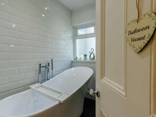 a white bathroom with a bath tub and a window at 4 Bed in Brixham 90449 in Brixham