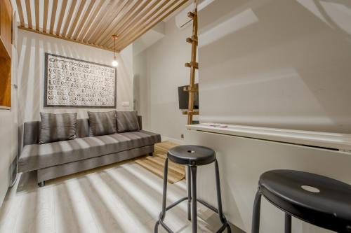 sala de estar con sofá y taburete en Apt con estilo - 5pax en zona Tirso-Centro, en Madrid