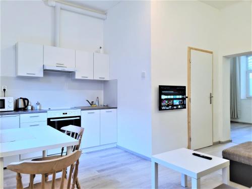 a kitchen with white cabinets and a table and chairs at Brno apartment in Brno
