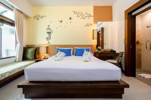 A2 Pool Resort - SHA Plus في فوكيت تاون: غرفة نوم مع سرير أبيض كبير مع وسائد زرقاء