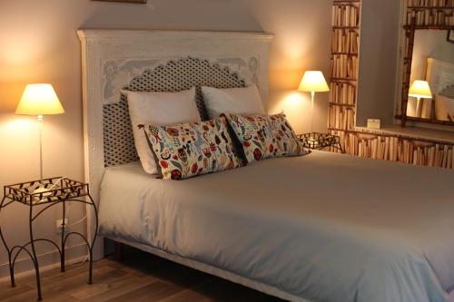 a bedroom with a bed with pillows and two lamps at Le Coteau du Seigneur in Laize-la-Ville
