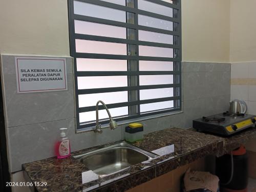 eine Küchentheke mit einem Waschbecken und einem Fenster in der Unterkunft Homestay Itqan Seri Iskandar in Seri Iskandar