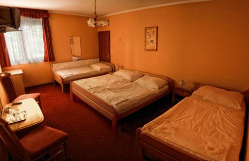 a hotel room with two beds and a chair at Euro Panzio in Debrecen