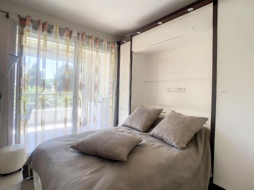 - une chambre dotée d'un lit avec des oreillers et d'une grande fenêtre dans l'établissement Cannes - 2 pièces quartier Palm Beach, à Cannes
