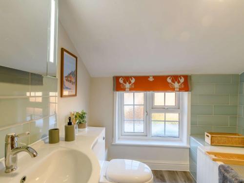 a bathroom with a sink and a toilet and a window at 2 Bed in Foulsham 90675 in Foulsham