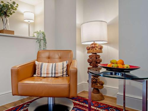 a room with a chair and a table with a bowl of fruit at 3 Bed in Fakenham 90681 in Fakenham