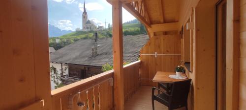 uma varanda com uma mesa e vista para uma igreja em Apartment 4 em Prato alla Drava
