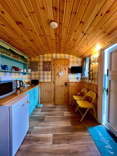 a kitchen with blue cabinets and a wooden ceiling at Shepherds hut Greencastle in Omagh