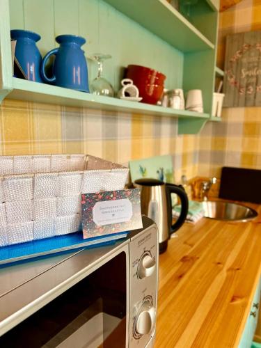 a kitchen with a microwave with a box on top of it at Shepherds hut Greencastle in Omagh