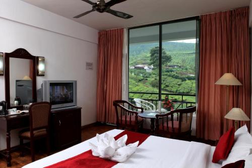 a hotel room with a bed and a desk and a window at Hotel C7 Munnar in Munnar
