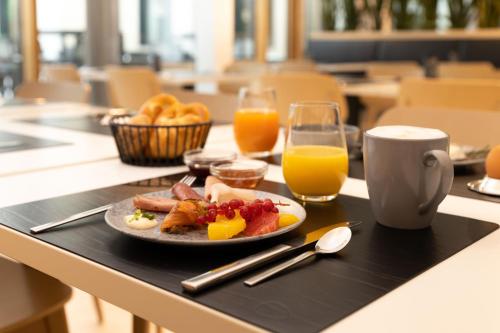a breakfast tray with a plate of food and orange juice at DEKRA Congresshotel Wart in Altensteig