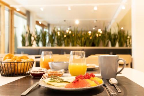 a table with a plate of fruit and orange juice at DEKRA Congresshotel Wart in Altensteig