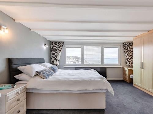 a bedroom with a large bed and two windows at 3 Bed in Brixham 90565 in Brixham