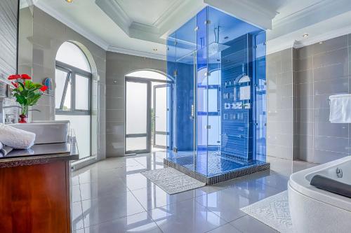y baño con ducha azul y bañera. en Villa Tasha Luxury Suites, Lanseria, en Johannesburgo