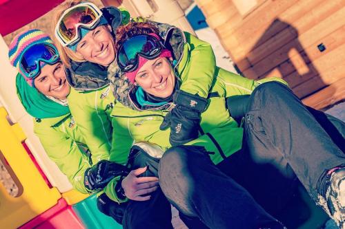 Trois personnes posent une photo avec un snowboard dans l'établissement Naturae Lodge, à Alleghe