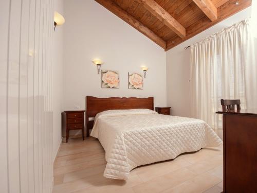 ein weißes Schlafzimmer mit einem Bett und einer Holzdecke in der Unterkunft La Dimora di Federico in Castel Lagopesole